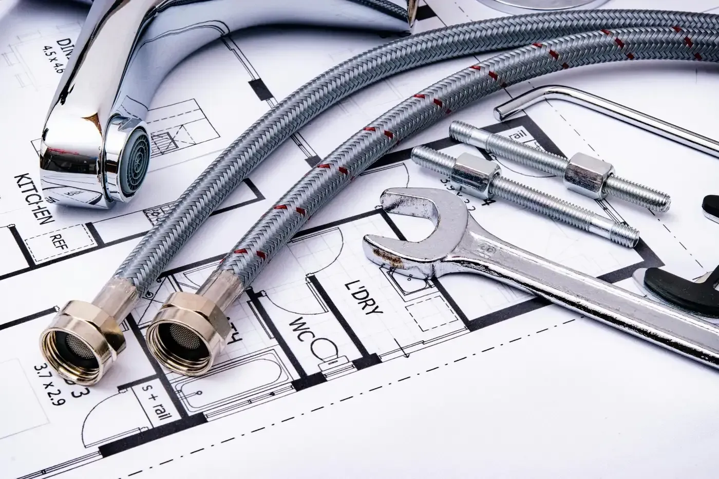 Mangueras trenzadas flexibles, accesorios metálicos y herramientas de plomería en planos arquitectónicos