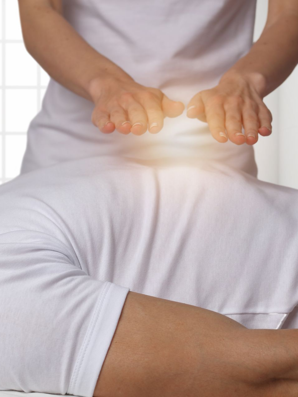 Personne vêtue de vêtements blancs, les mains brillantes au-dessus du corps d'une autre personne, suggérant une guérison énergétique.