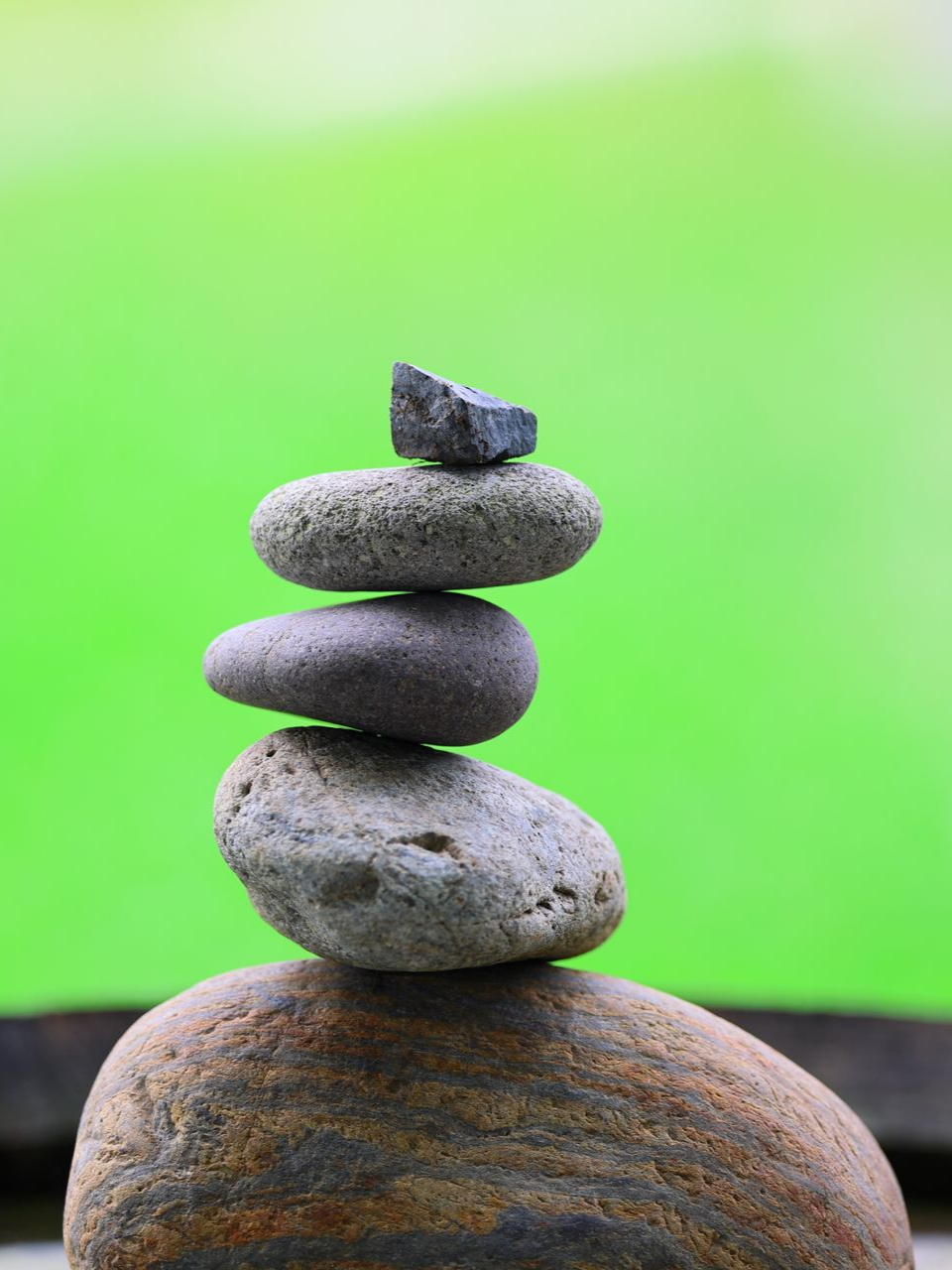 Pierres grises empilées sur un fond vert flou, ressemblant à un cairn.