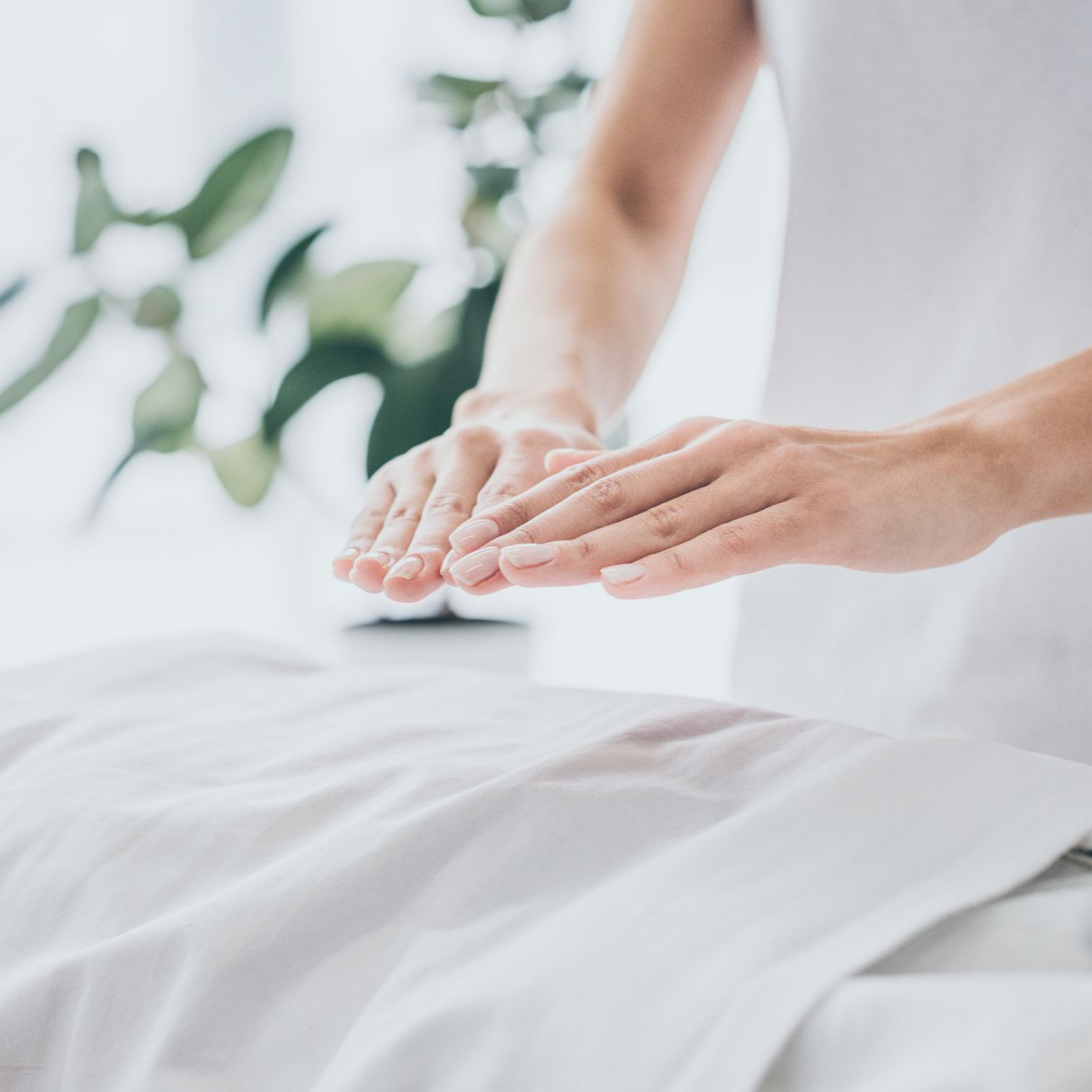Les mains d'une personne planant au-dessus d'une personne sur une table de massage, pratiquant le Reiki.
