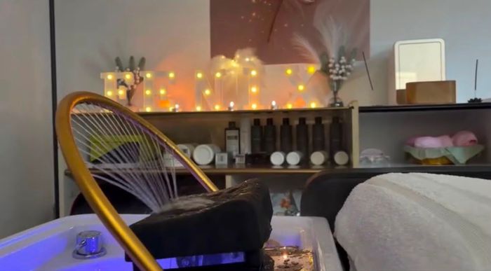 Mujer con cabello castaño largo en un salón iluminado por el sol, mostrada de perfil con reflejos brillantes.