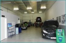 Interior de un taller mecánico con varios coches y equipos de reparación