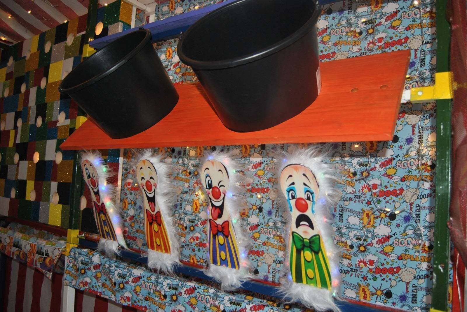 Mural de payasos con dos sombreros negros y figuras pintadas de colores sobre una pared estampada.
