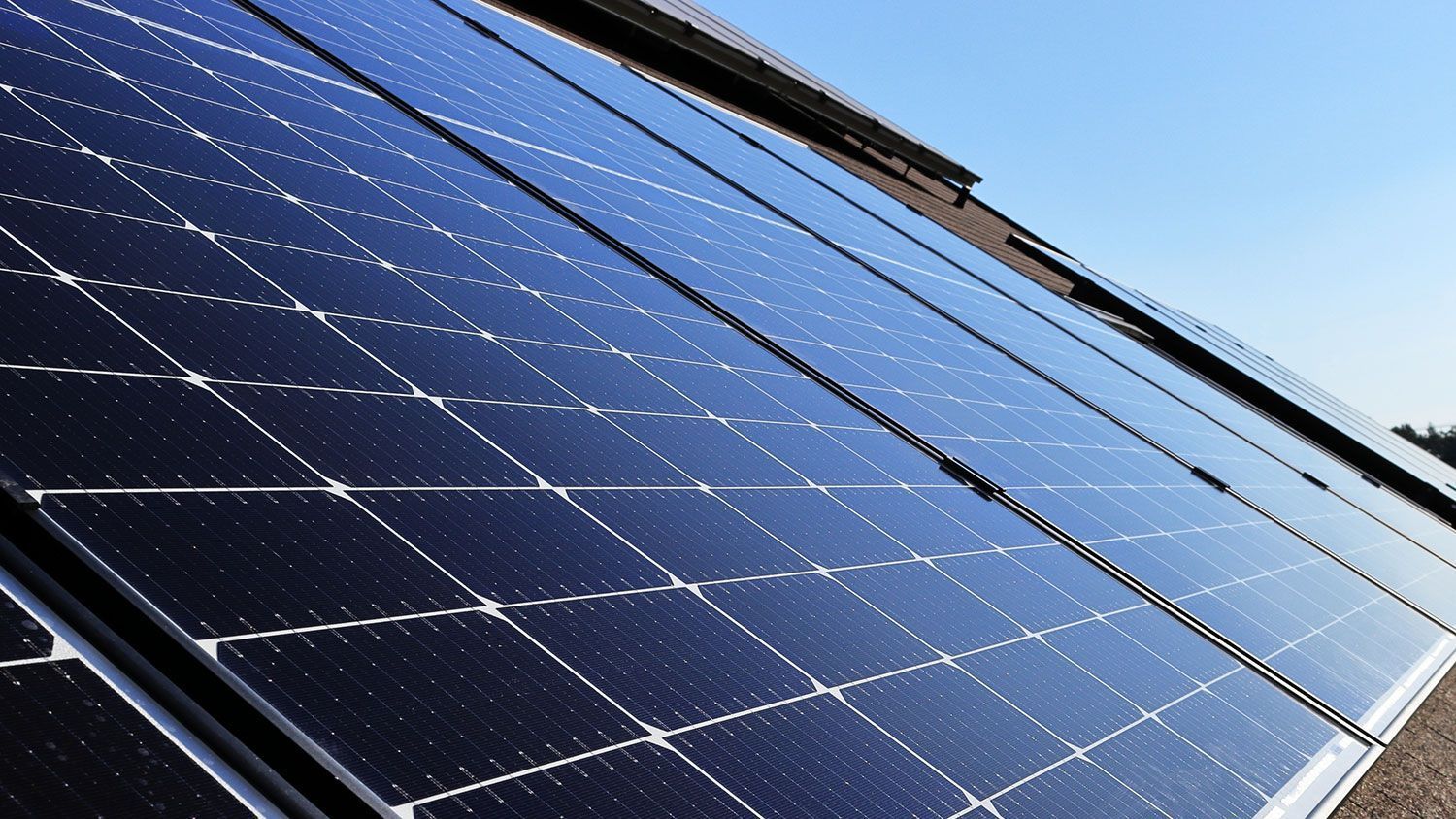 Die Solarpaneele sind zum Himmel geneigt und reflektieren das Sonnenlicht auf ein Dach.
