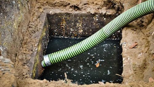 Se utiliza una manguera verde para bombear agua a un tanque séptico.