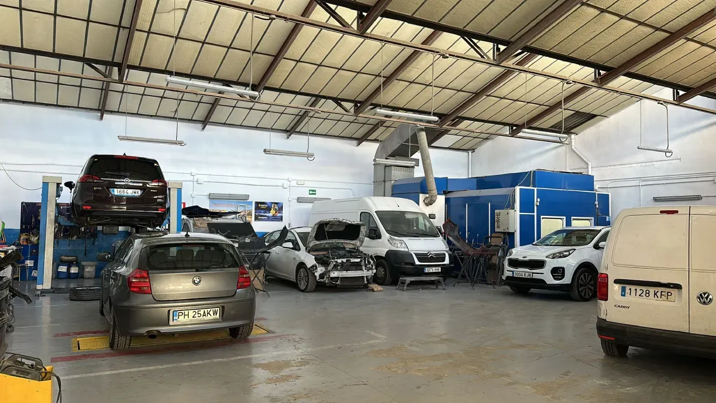 Furgoneta roja siendo pintada en una cabina de pintura blanca.