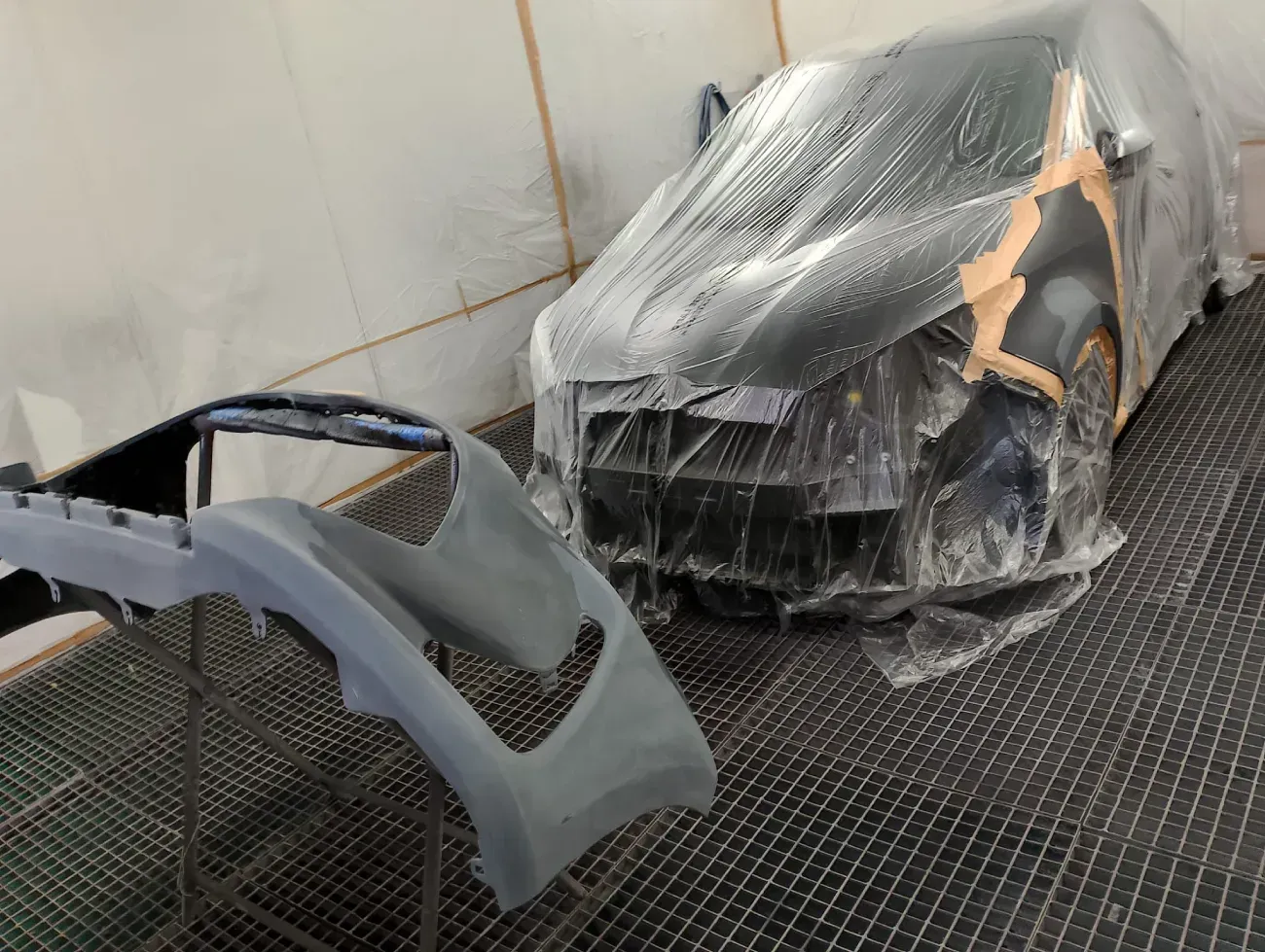 Furgoneta roja siendo pintada en una cabina de pintura blanca.