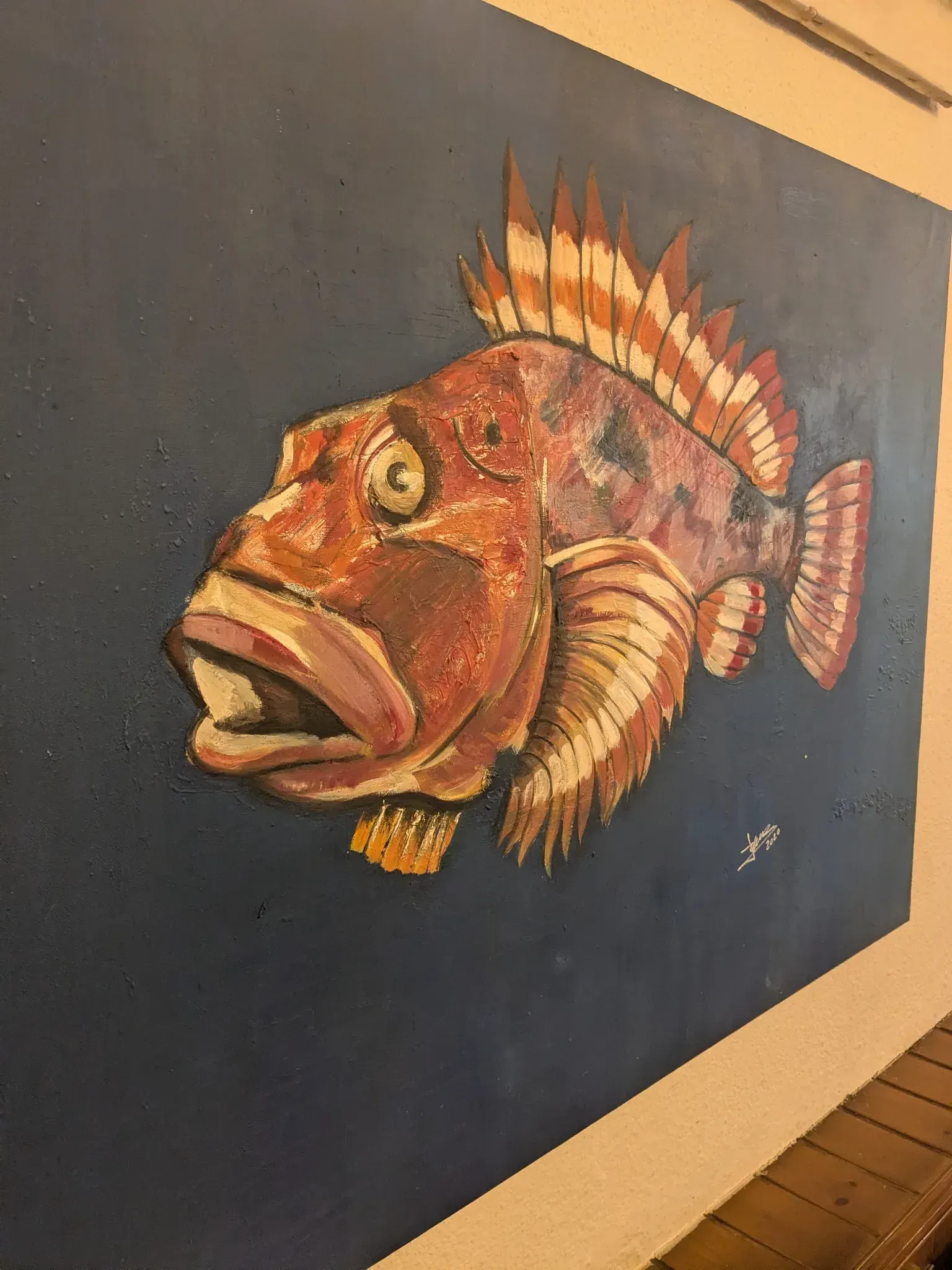 Mural de pez rojo y morado con la boca abierta sobre una pared azul marino.