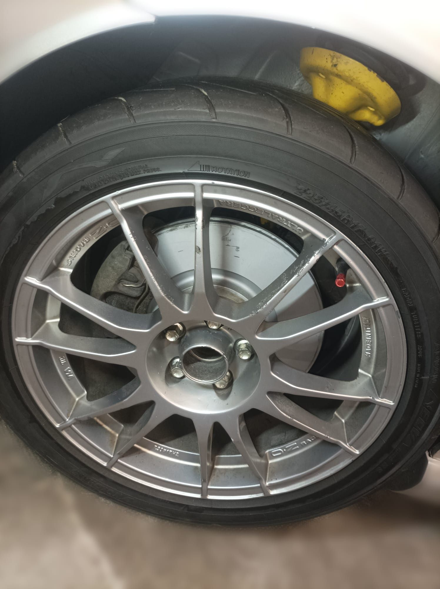 Un primer plano de una rueda de coche con un parachoques amarillo.