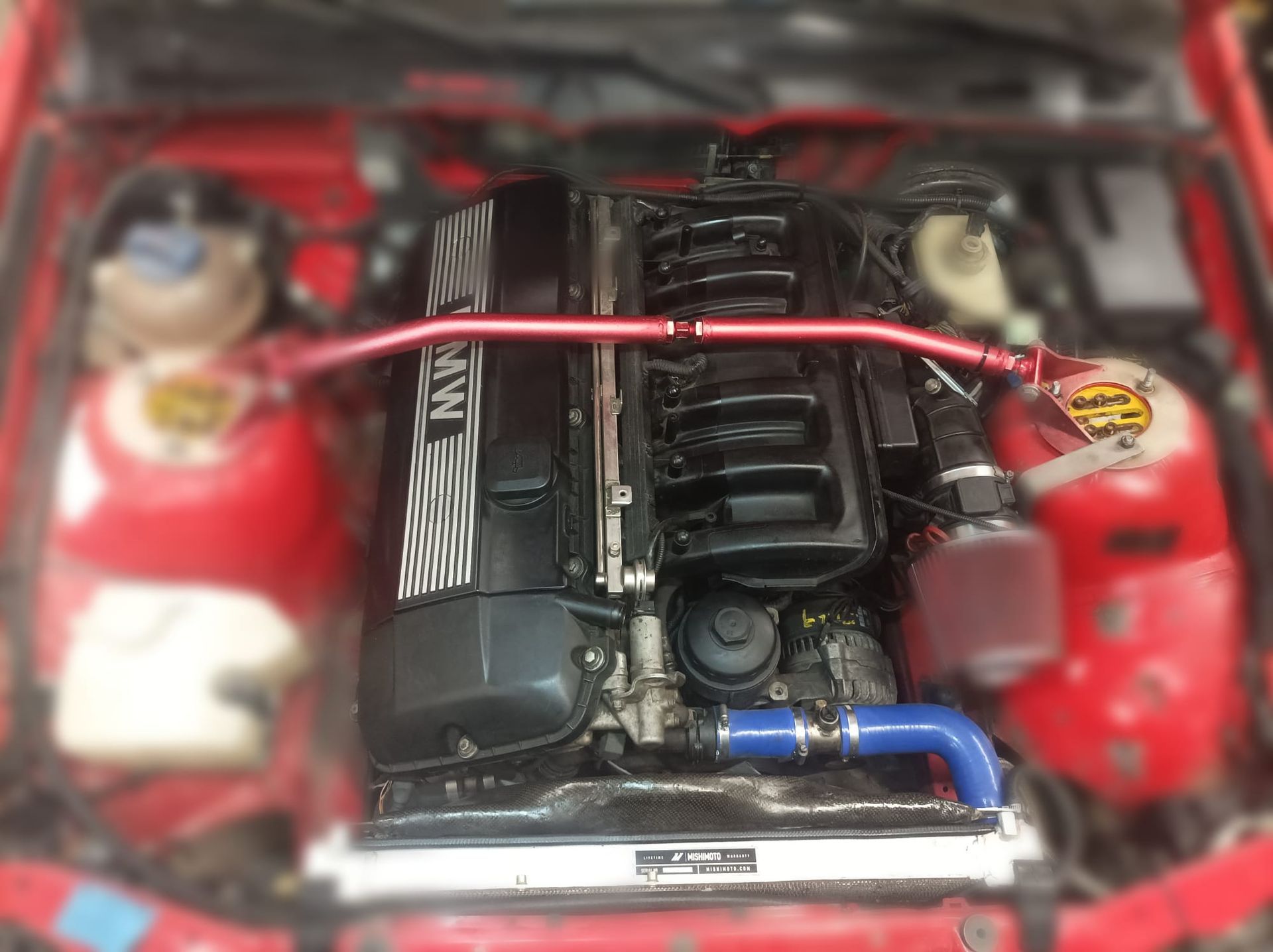 Un primer plano del motor de un coche rojo.