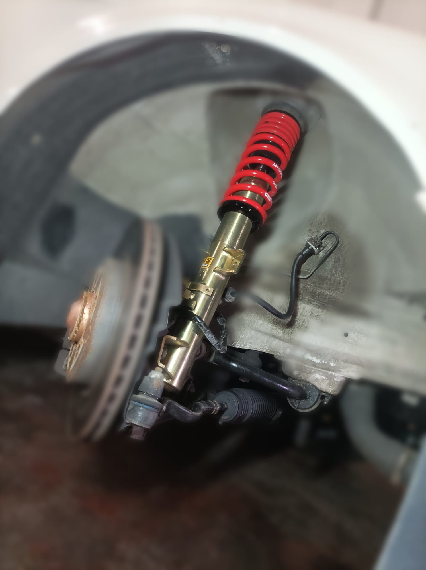 Un primer plano de la suspensión de un automóvil con un amortiguador rojo.