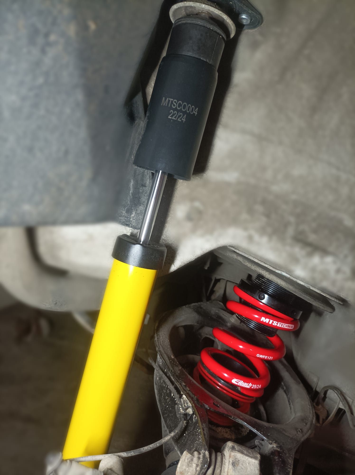 Un amortiguador amarillo con un resorte unido a él.