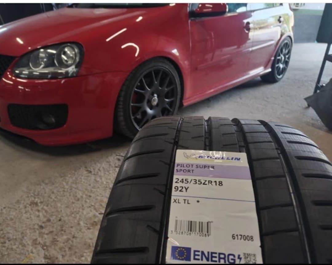 Un coche rojo está aparcado al lado de un neumático que dice energía.