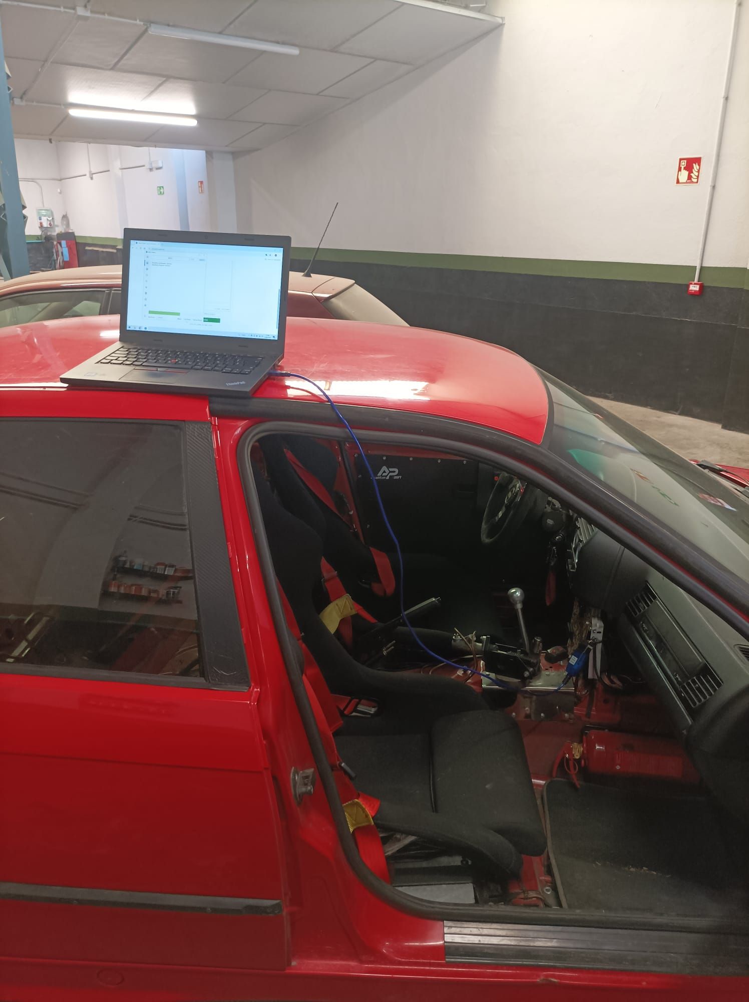 Un coche rojo con un ordenador portátil encima.