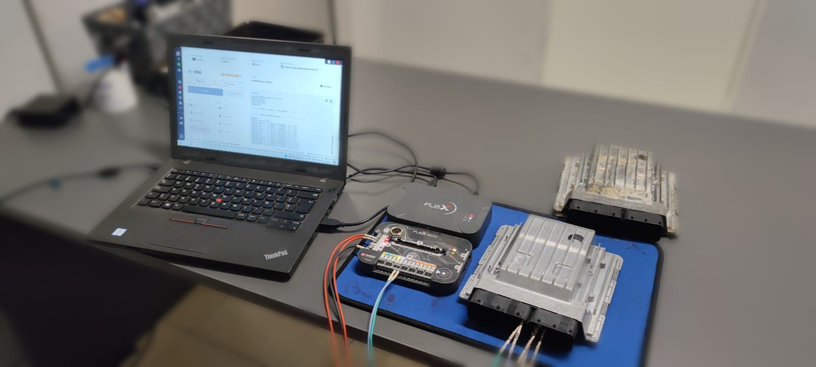 Una computadora portátil está sobre un escritorio al lado de un montón de dispositivos electrónicos.