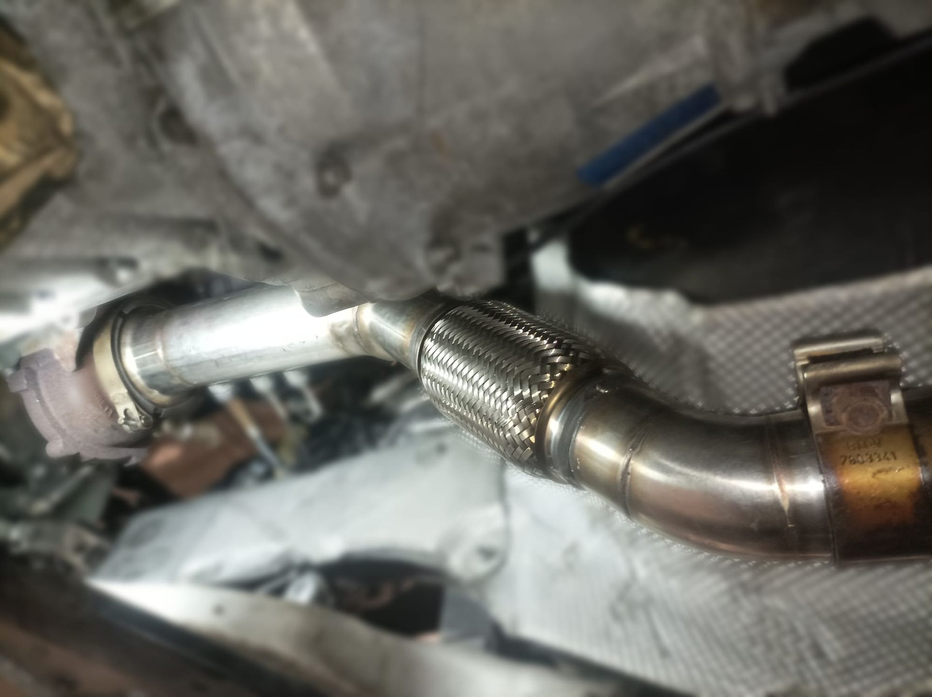 Un primer plano de un tubo de metal conectado al motor de un automóvil.