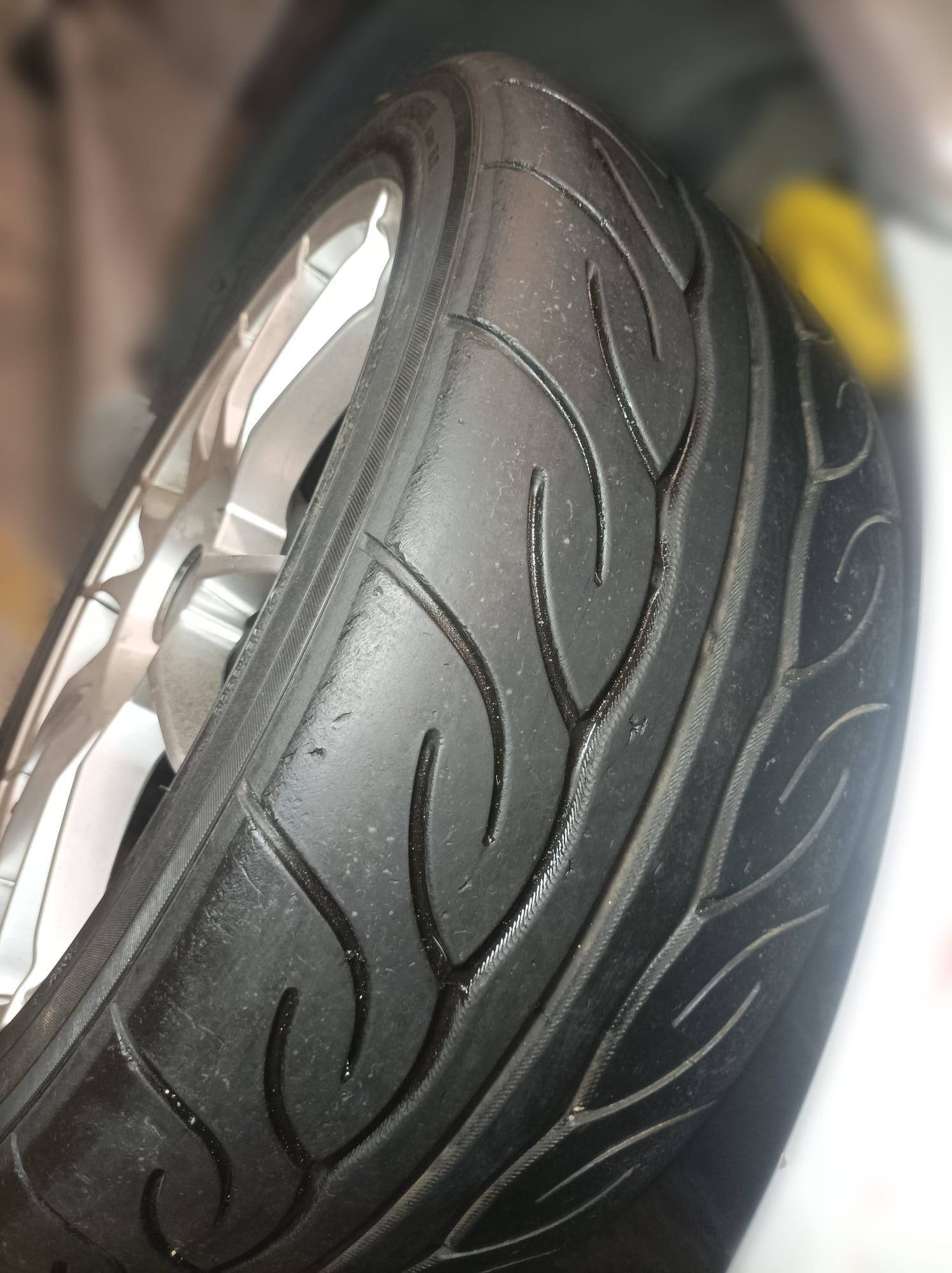 Un primer plano de un neumático con una rueda al fondo.