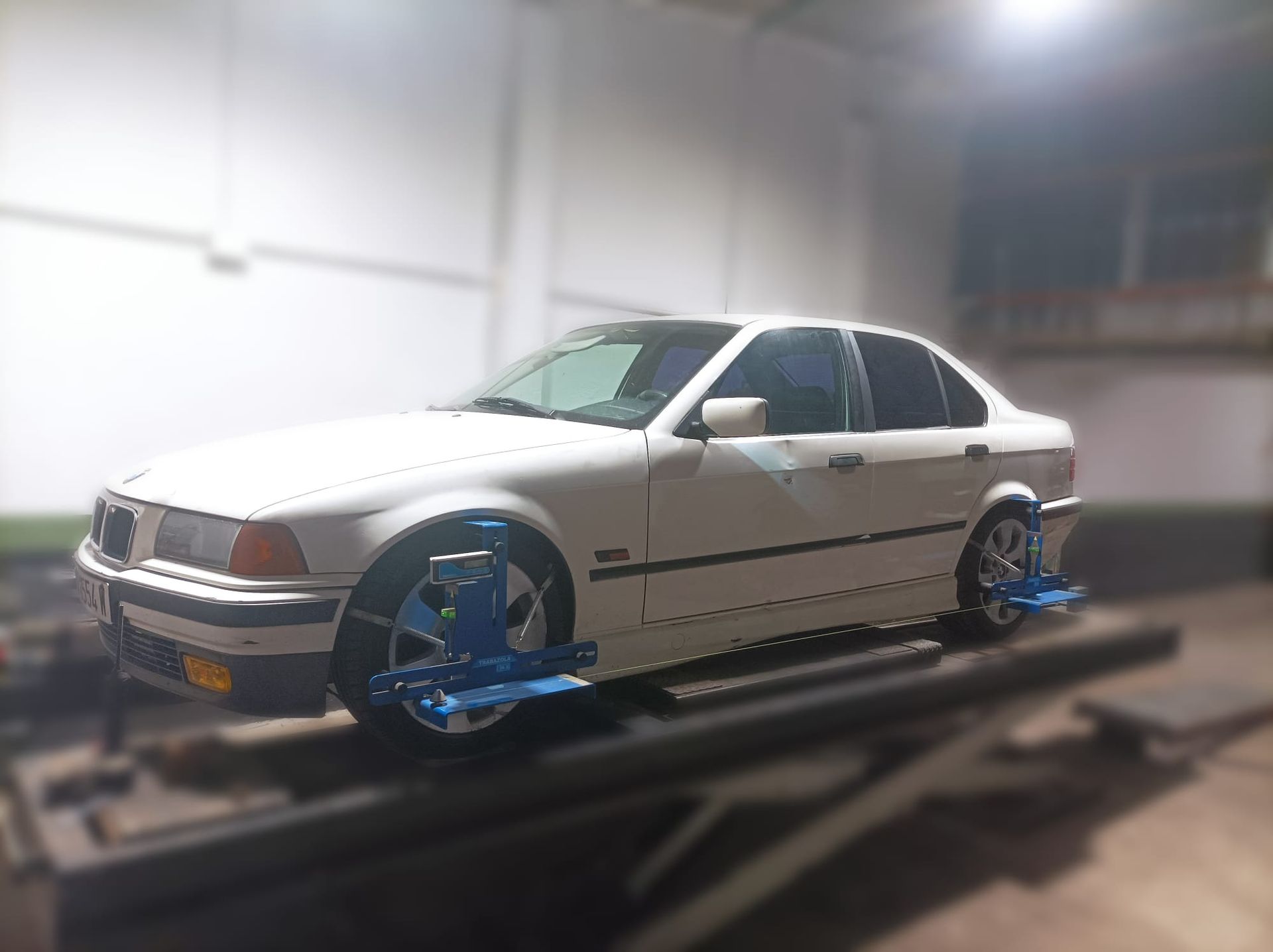 Un coche blanco está estacionado encima de un ascensor en un garaje.