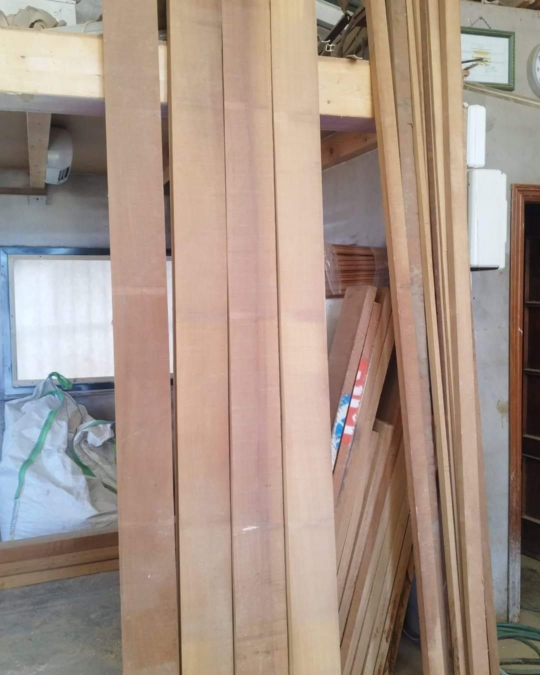 Montones de tablas y tablones de madera apilados en un área de almacenamiento dentro de un taller.
