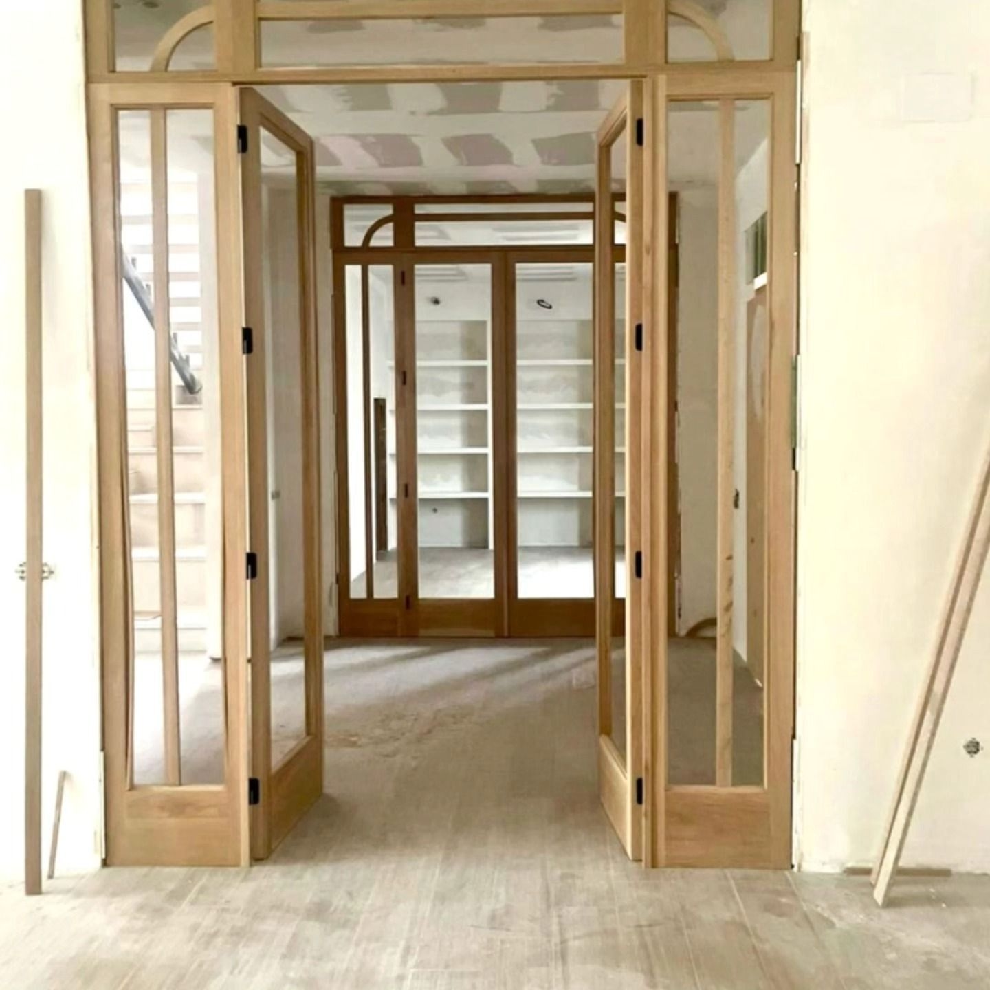 Interior vacío con marcos de puertas de madera sin terminar y una habitación con estanterías empotradas.
