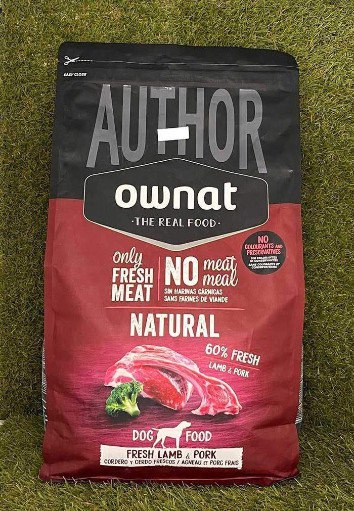 Bolsa roja y negra de comida para perros Ownat sobre césped, etiquetada como carne natural y fresca.