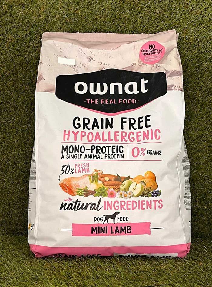 Bolsa de comida hipoalergénica sin cereales Ownat para perros pequeños con forma de cordero sobre fondo de hierba.