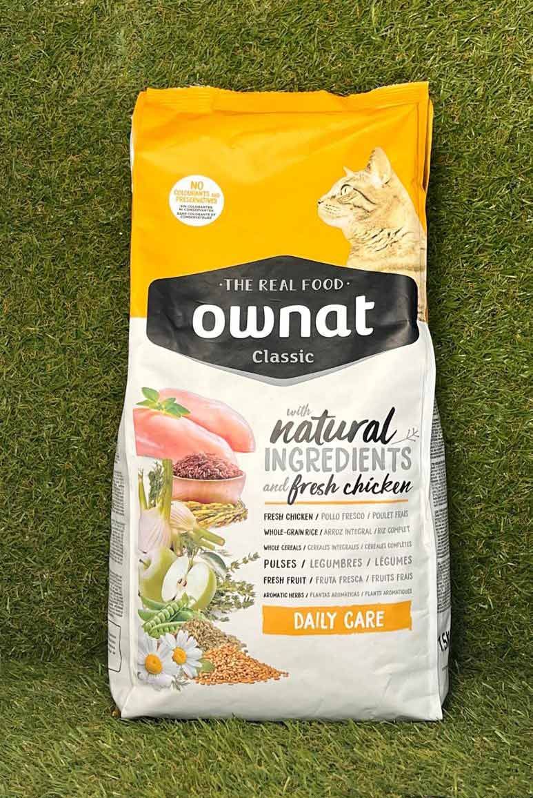 Bolsa de comida para gatos Owna de color naranja sobre el césped, etiquetada como 