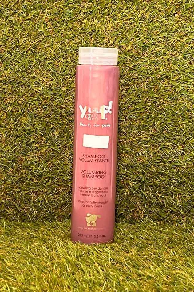 Botella de champú rosa sobre fondo de césped verde