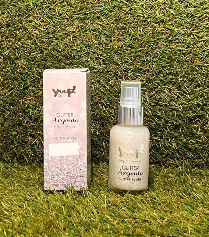 Frasco de perfume y caja rosa sobre fondo de césped verde