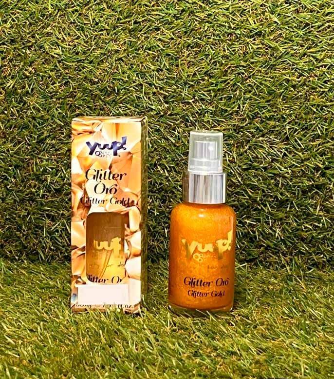 Botella de spray de aceite corporal naranja junto a una caja a juego sobre fondo de césped.