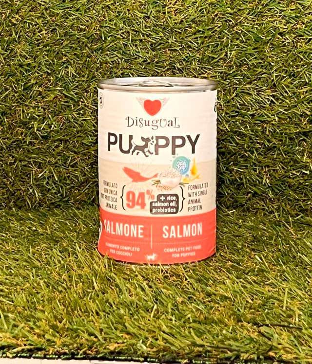 Lata de comida para perros Disugual Puppy de salmón sobre fondo de césped.
