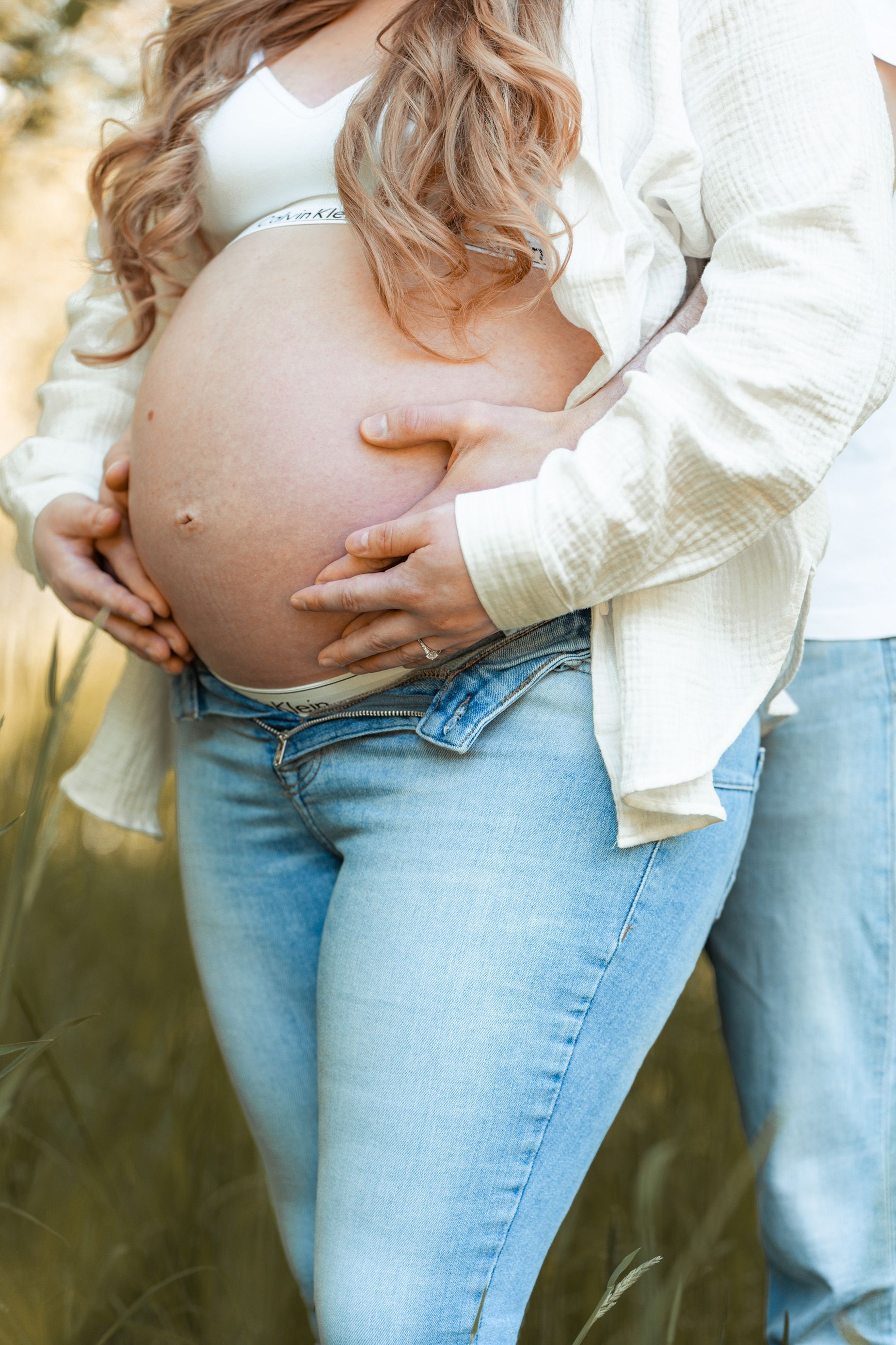 Babybauchshooting in Bremen – natürliche Babybauchfotos draußen mit liebevollen Umarmungen im Grünen.