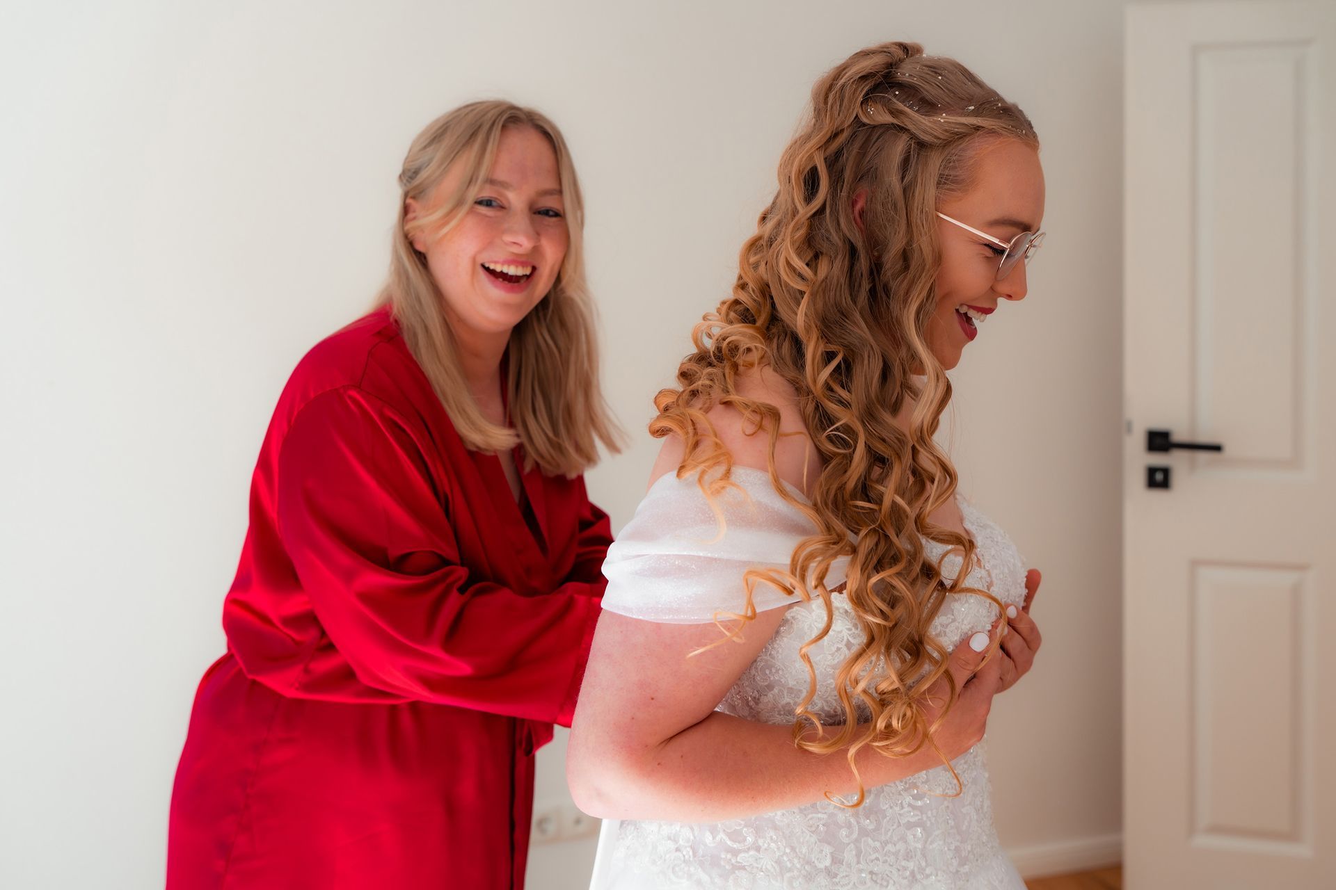 Braut wird beim Getting Ready von ihrer Schwester für die kirchliche Hochzeit in Bremen eingekleidet