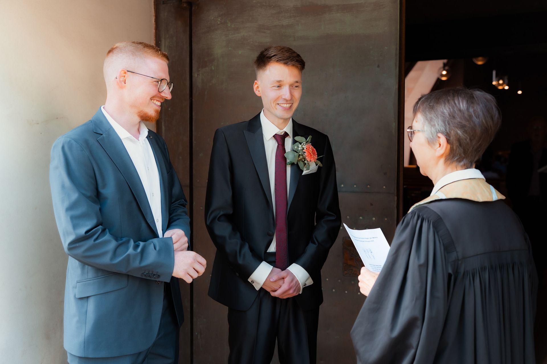 Bräutigam und Trauzeuge unterhalten sich vor der kirchlichen Trauung in Bremen mit der Pastorin.
