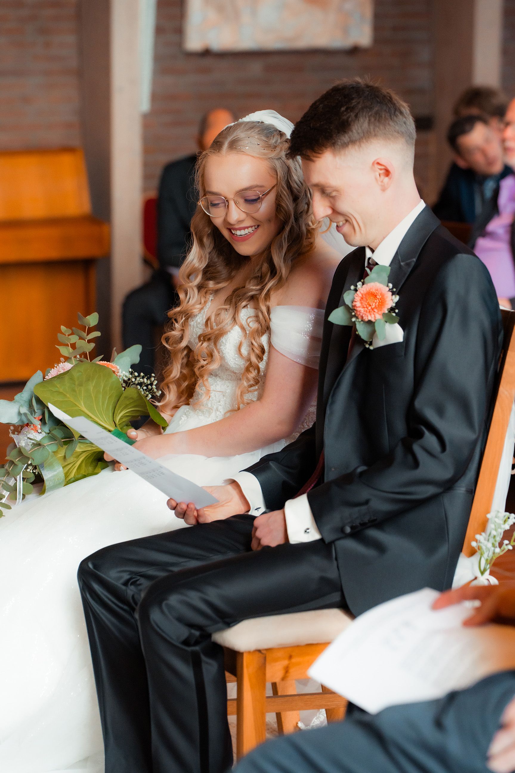 Lächelndes Brautpaar sitzt eng beieinander während der Trauzeremonie in der Melanchthon-Kirche in Bremen.