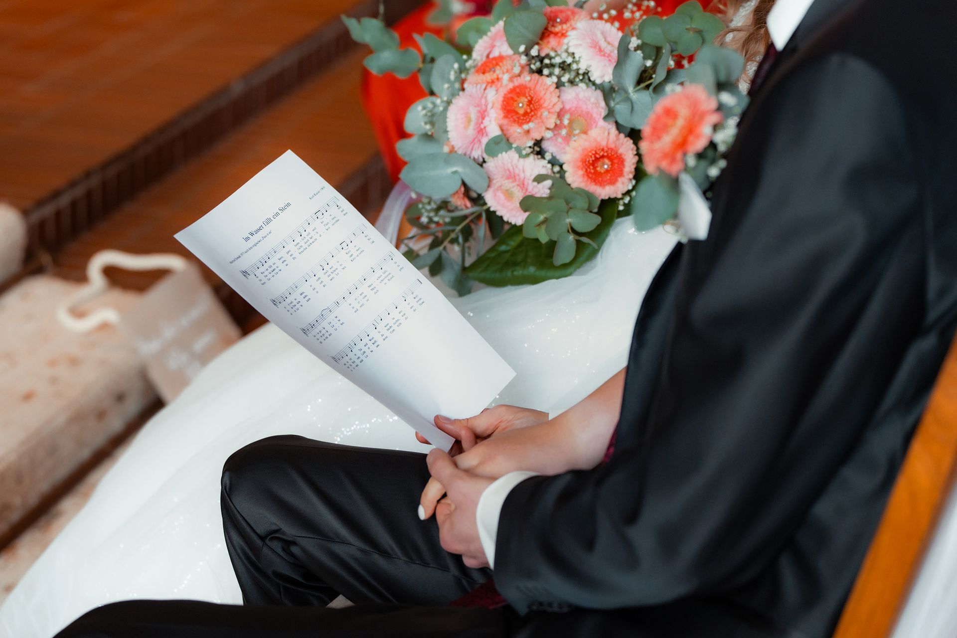 Bräutigam hält Liedblatt während der kirchlichen Trauung in Bremen neben einem Brautstrauß.