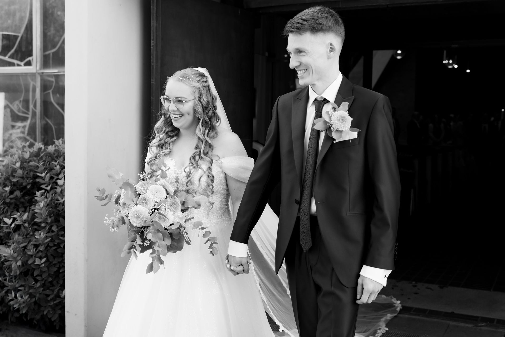 Das Brautpaar lächelt glücklich beim Auszug aus der Kirche nach der Trauung in Bremen, umgeben von festlicher Stimmung.