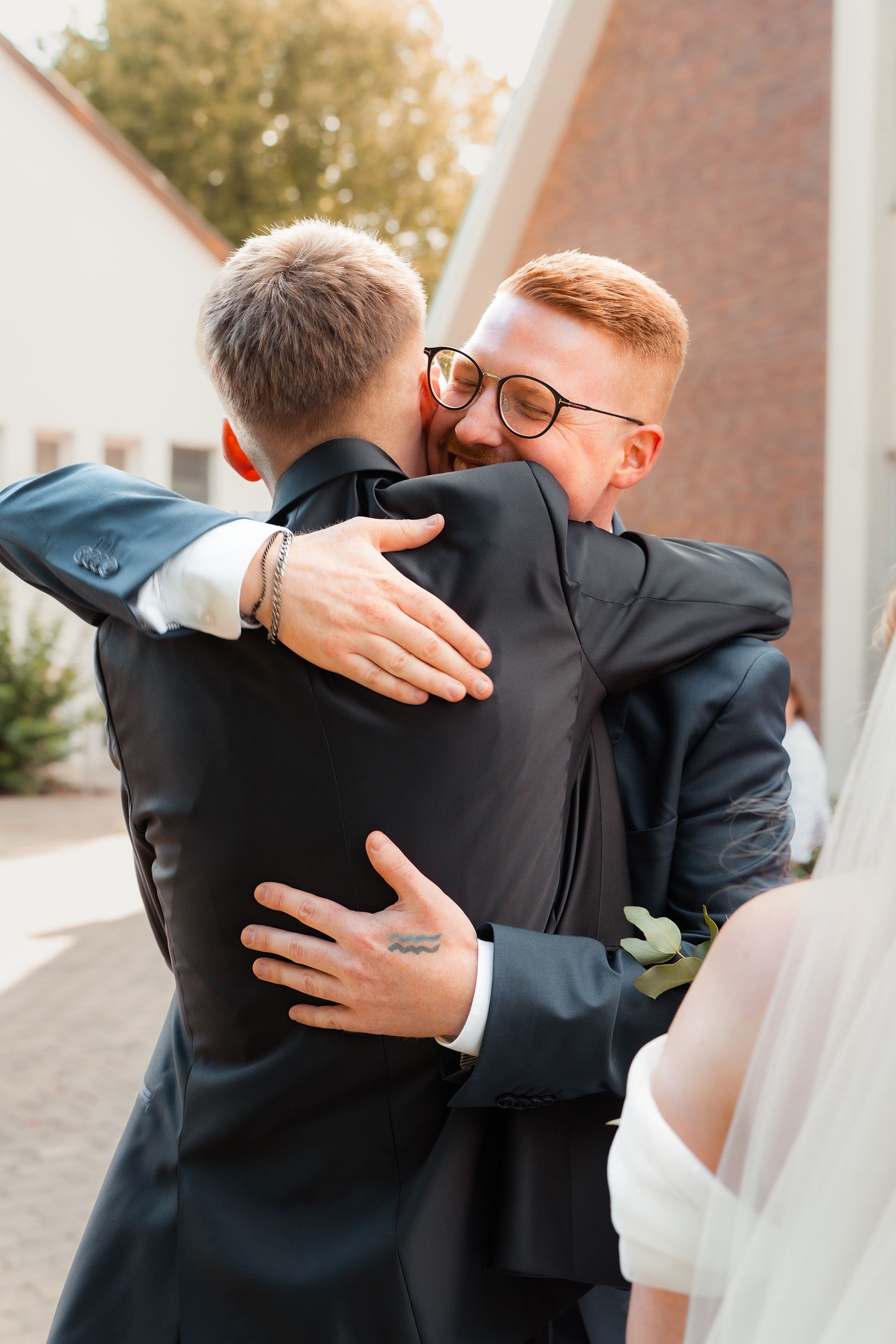 Emotionale Umarmung zweier Gäste bei der Hochzeitsgratulation vor der Kirche in Bremen.