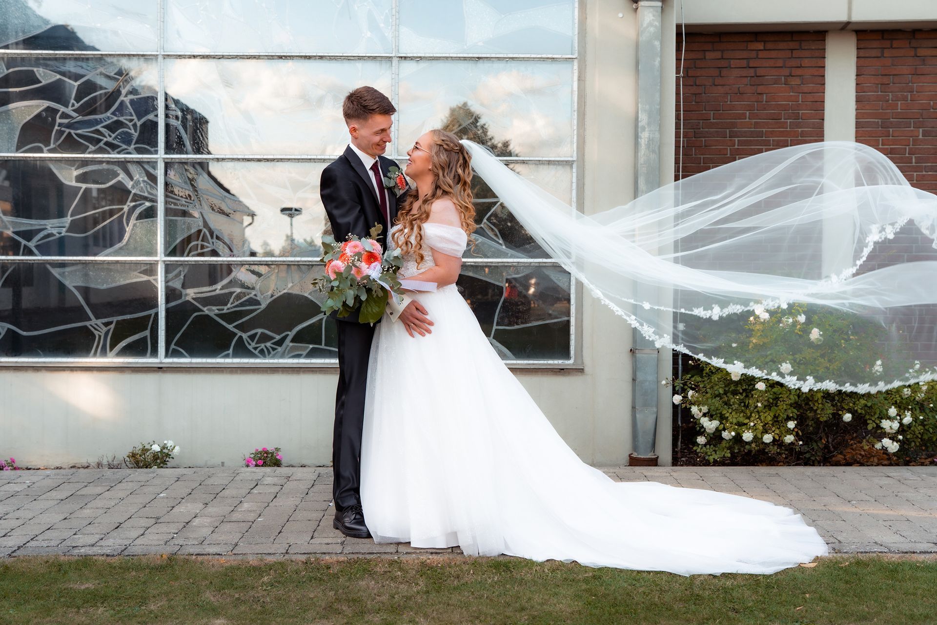 Brautpaarfotos vor der Kirche in Bremen mit wehendem Schleier.