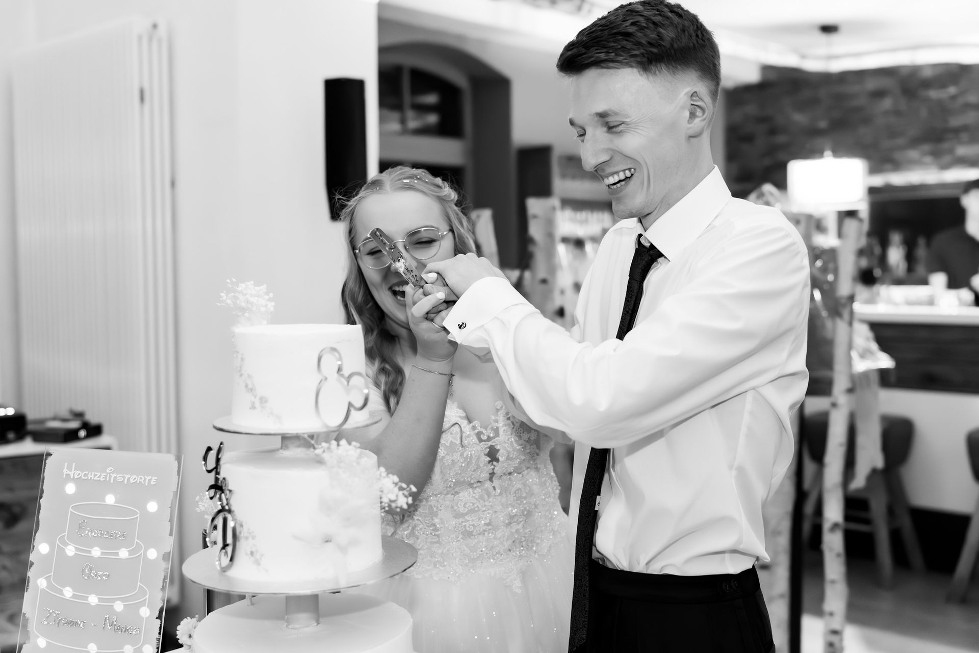 Brautpaar schneidet gemeinsam die Hochzeitstorte bei der Feier in Bremen an.