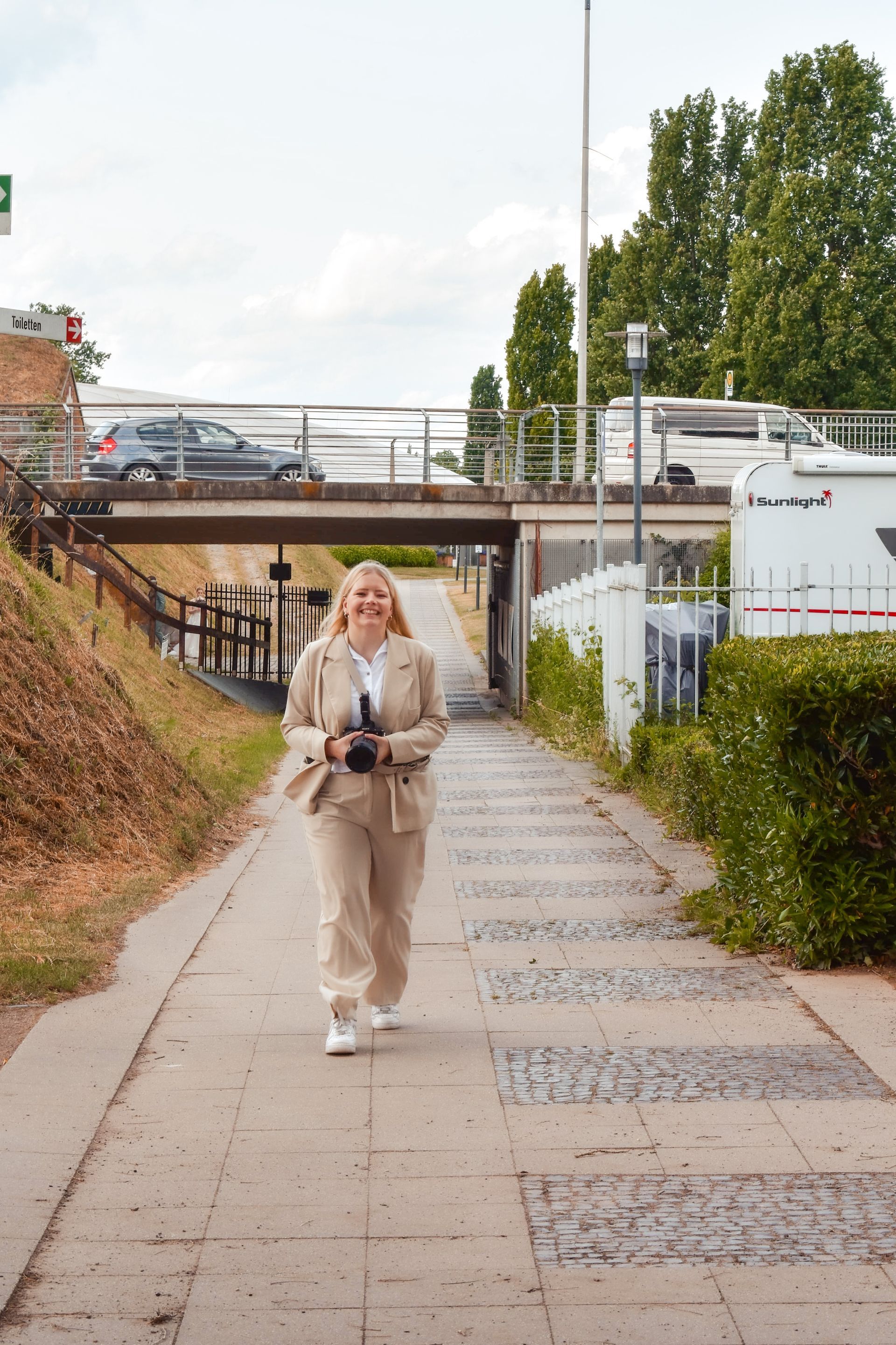 Fotografin Jenny Larrabe läuft unter eine Brücke zurück zur Hochzeitsgesellschaft zurück und lächelt dabei.