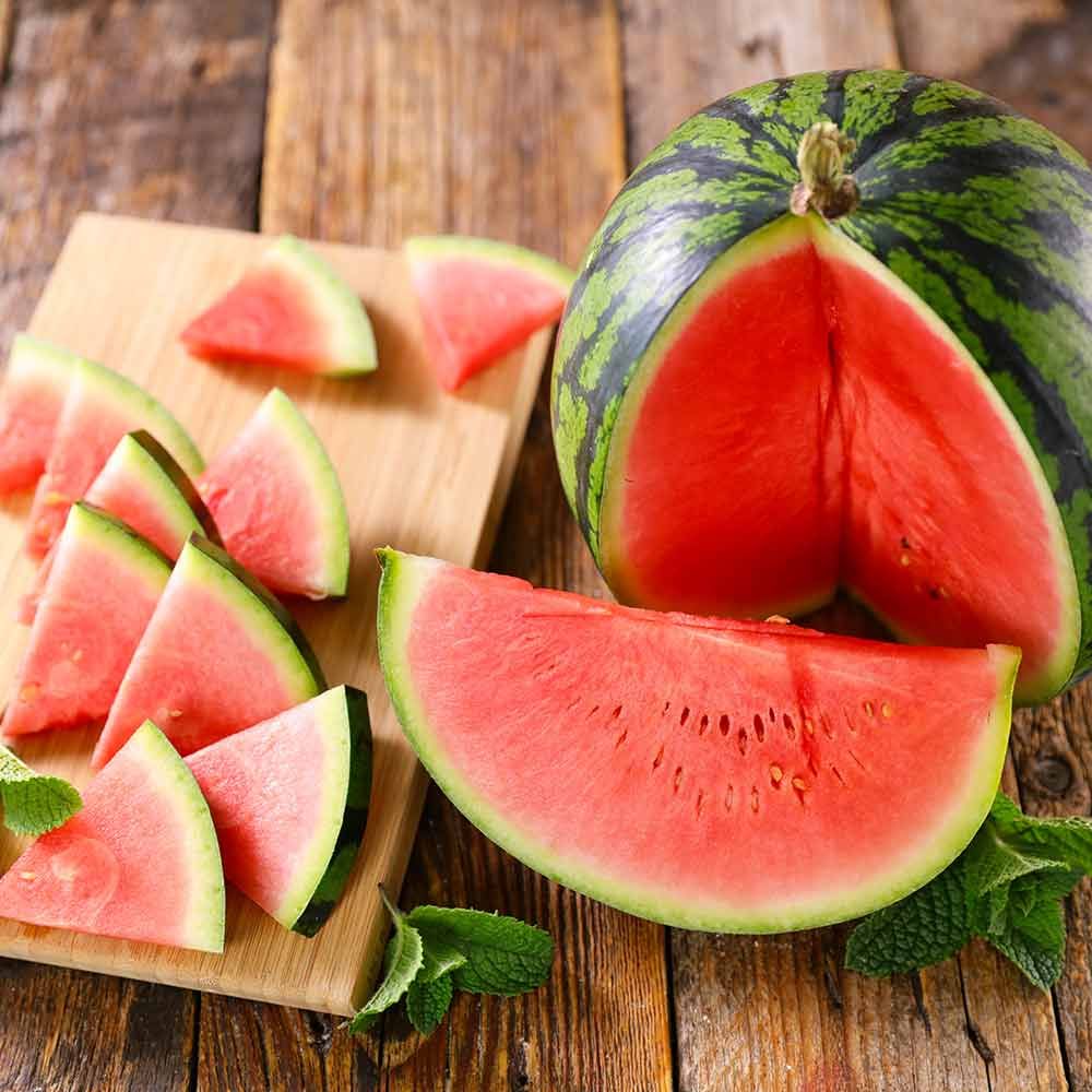 Eine Wassermelone wird auf einem Holztisch halbiert
