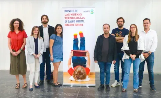 Un grupo de ocho personas de pie frente a una pancarta sobre el impacto de las nuevas tecnologías en la salud mental.