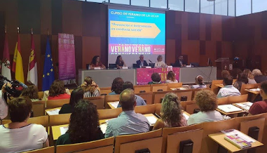 Una sala con personas sentadas en filas frente a un panel de oradores