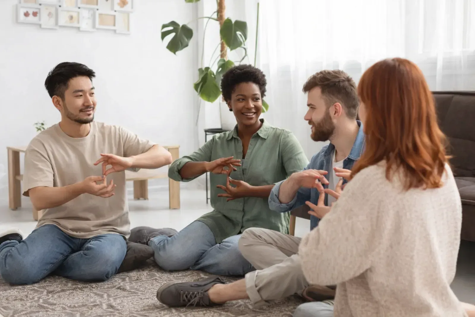 Cuatro personas están sentadas en círculo sobre una alfombra en una