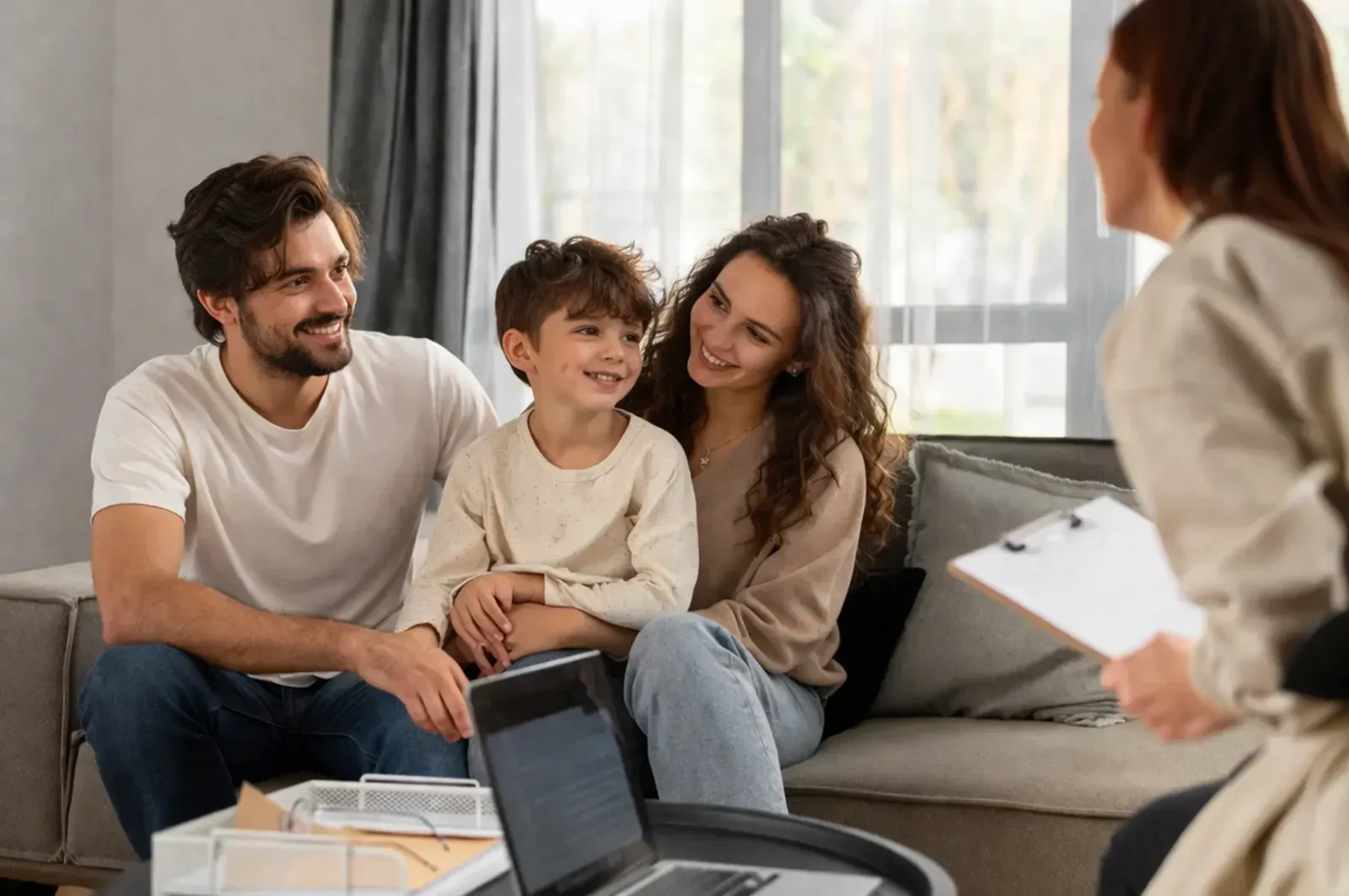 Una familia está sentada en un sofá en una habitación luminosa