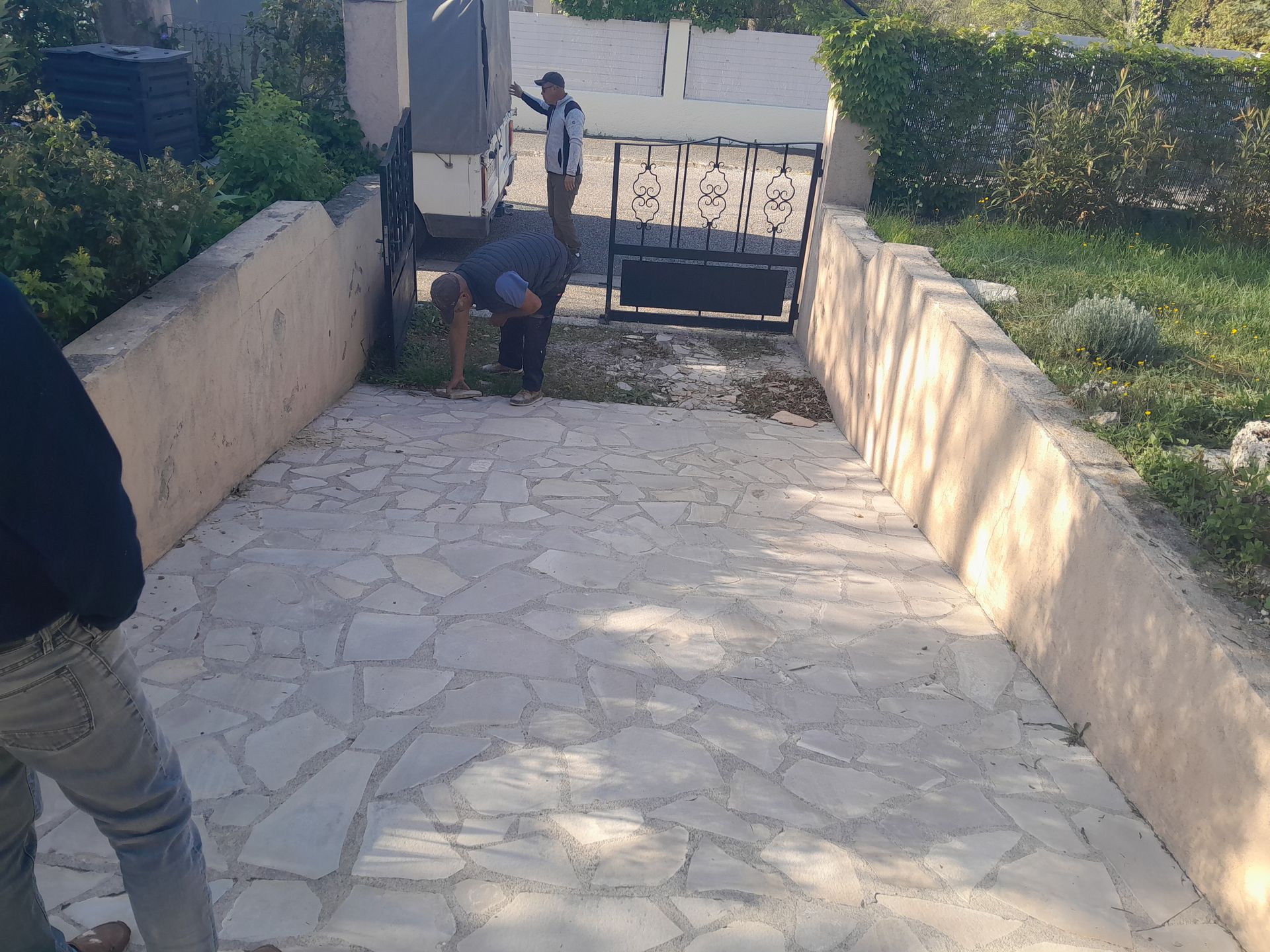 Des gens nettoient un chemin de pierre menant à une porte. Un homme est penché près de la porte et balaie les débris.