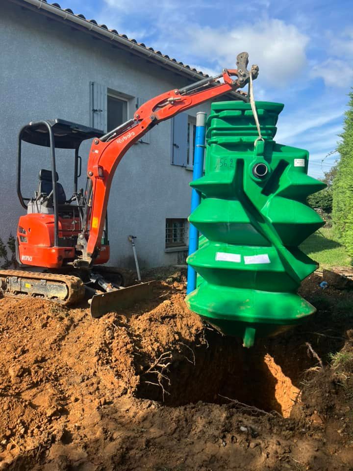 Une pelleteuse orange descend une grande fosse septique verte dans un trou creusé dans le sol près d'une maison.