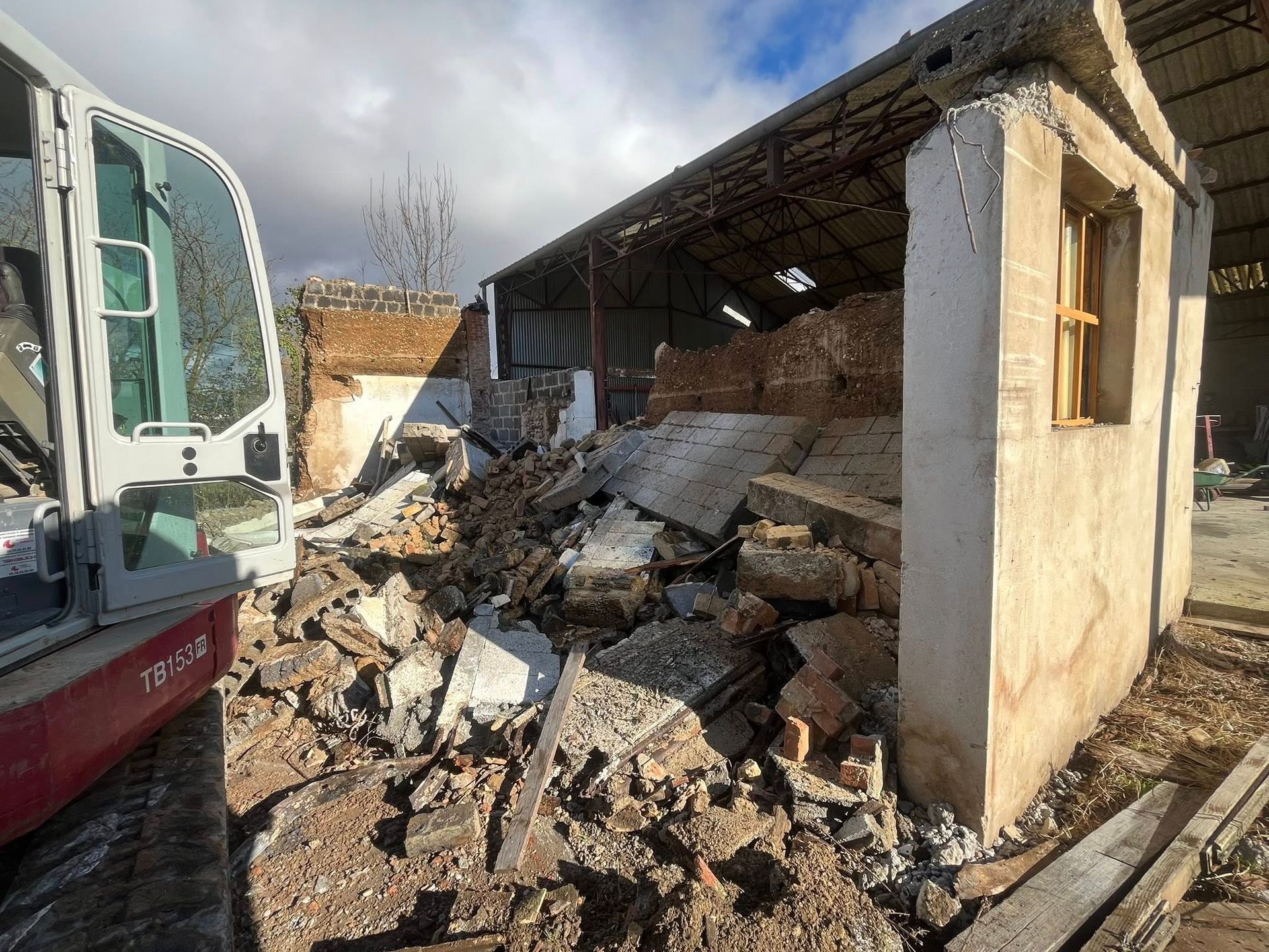 Débris d'un bâtiment démoli, vue extérieure avec une excavatrice. Journée ensoleillée.