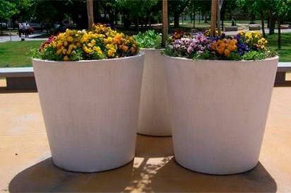 Dos macetas blancas llenas de flores están sobre una mesa.